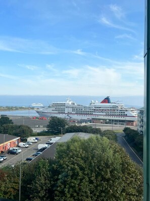 Blick auf ein Kreuzfahrtschiff, das in einem Hafen liegt, mit blauem Himmel.