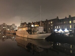 Ein großes, mehrstöckiges Schiff liegt im Hafen vor einer Gebäudebäckgrund.