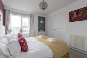 Ein Hotelzimmer mit Bett, Fenster, Tür und einer Wand mit einer Uhr und einem dekorativen Gegenstand.