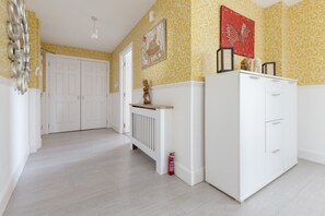 Un couloir avec un radiateur blanc, une armoire blanche et une porte donnant sur une autre pièce.