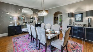 A dining area with a chandelier, a table set with plates, and a patterned rug. - Historic Group Retreat w/ Pool in Paducah (Paducah)