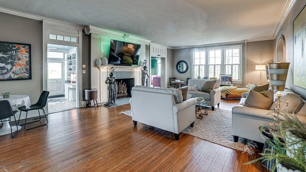 A spacious living room with a fireplace, a television, and a dining area with a table and chairs. - Historic Group Retreat w/ Pool in Paducah (Paducah)