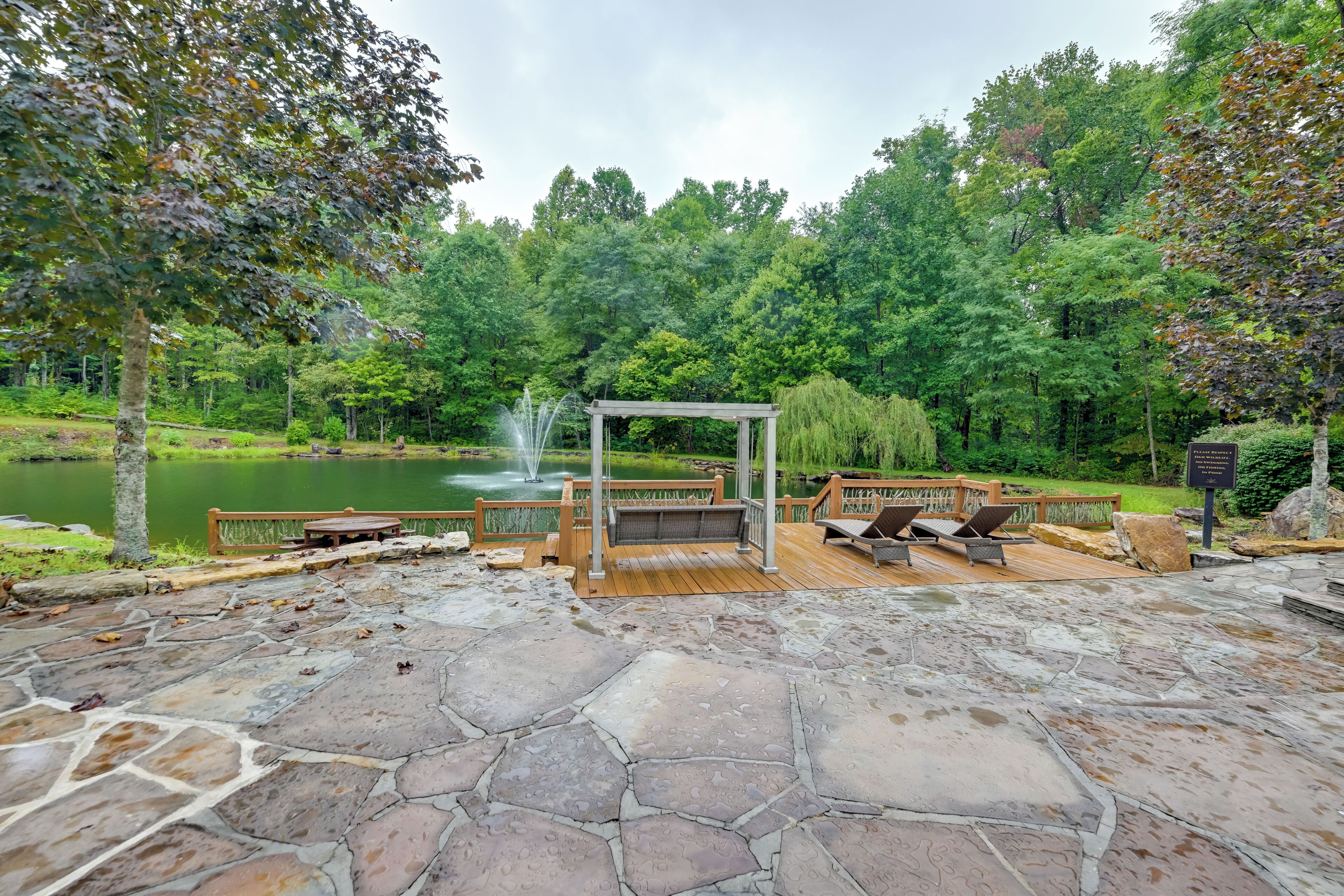 A stone deck with outdoor seating, a gazebo, and a pond with a fountain.