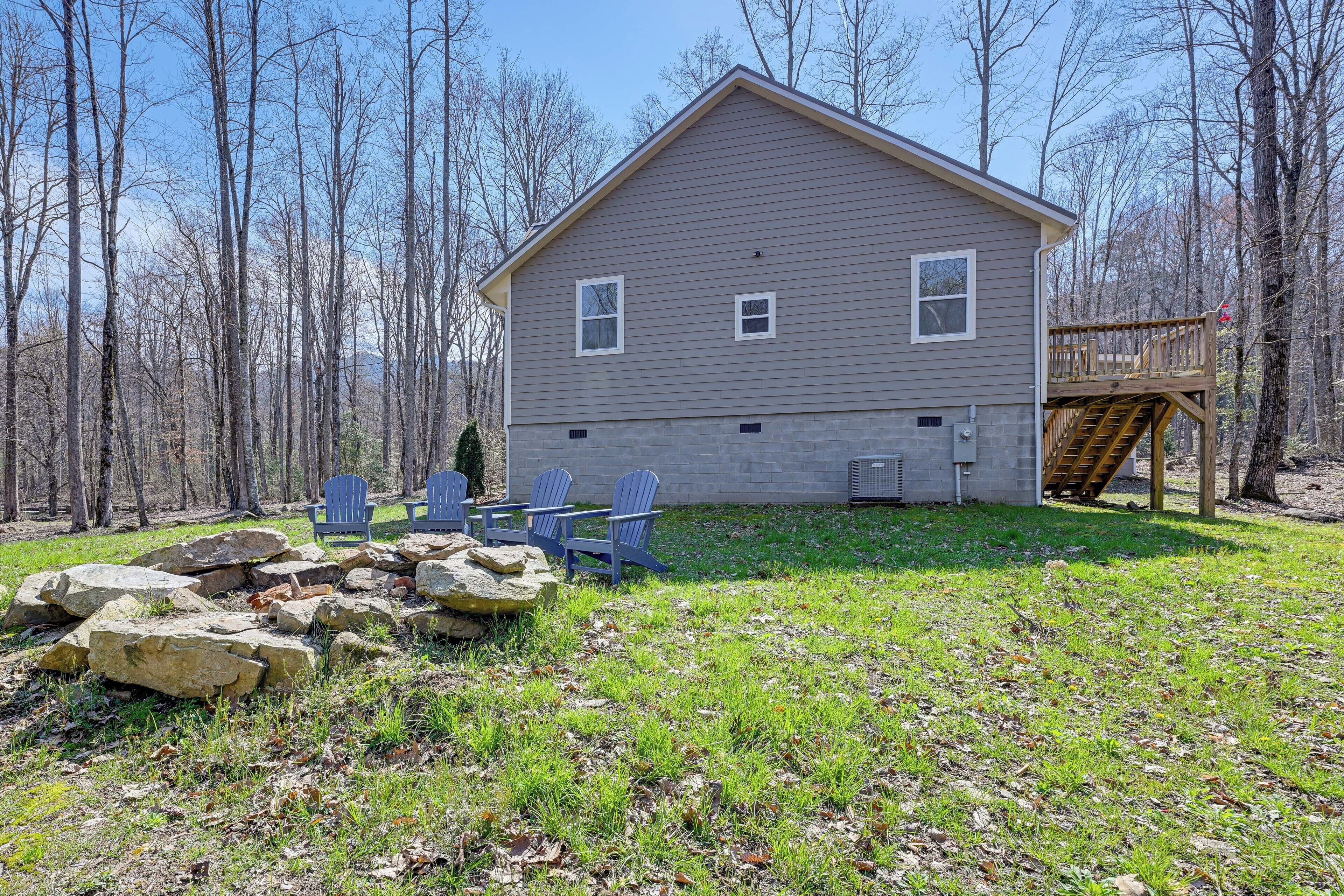 A two-story house with a deck, surrounded by trees.