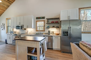 A modern kitchen with white cabinets, stainless steel appliances, and a wooden island. - Fire Pit w/ Pond: Modern Mtn Retreat in Smoky Mtns (Andrews)