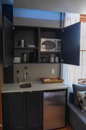 A compact kitchenette with a built-in microwave, a sink, and a compact refrigerator.