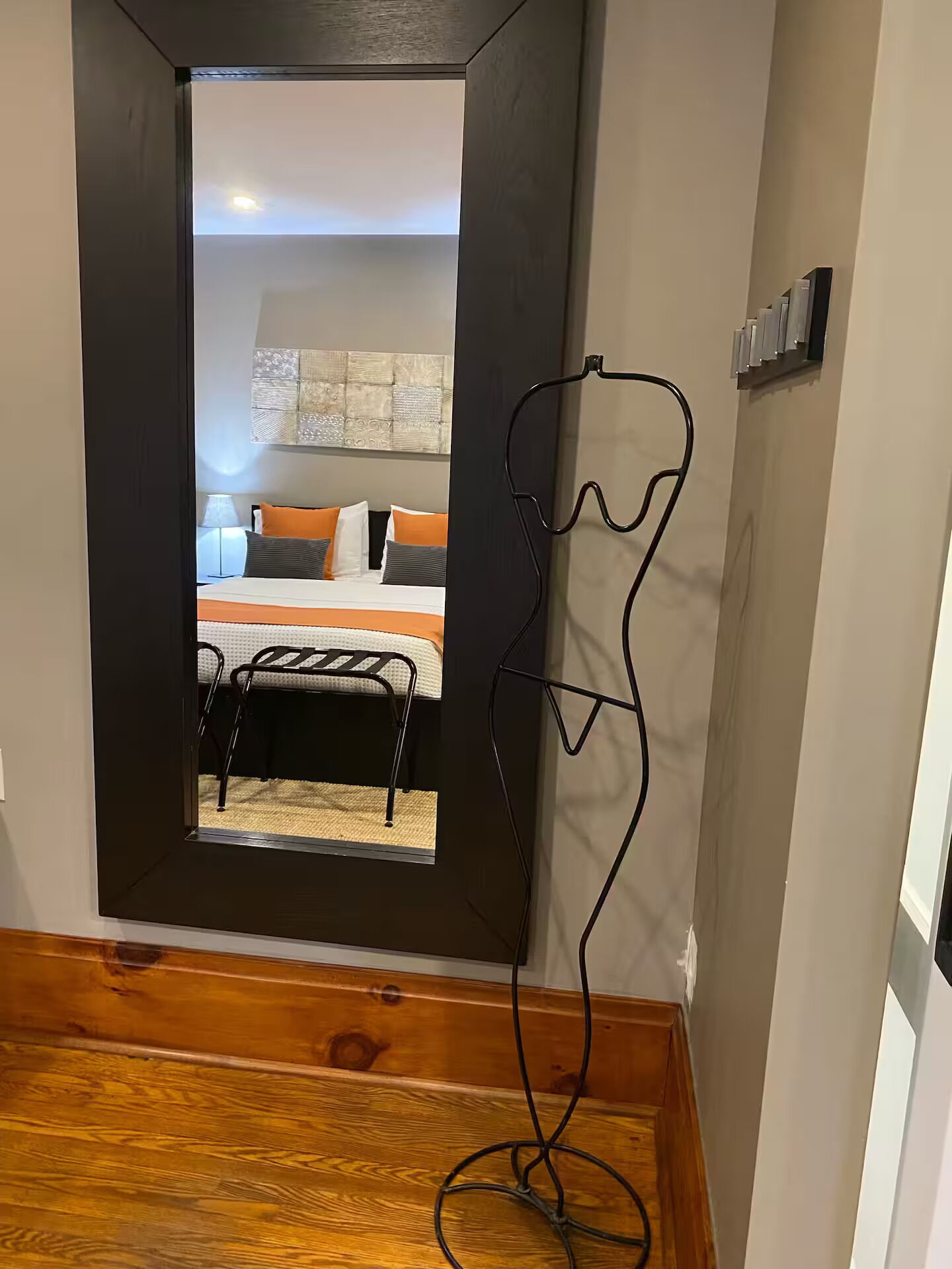 A doorway leading to a bedroom with a bed, pillows, and a bedside table.