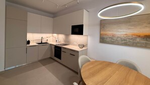 Una cocina moderna con armarios blancos, una mesa de comedor de madera y una lámpara colgante contemporánea.