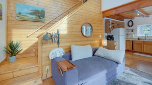A wooden interior with a sofa, a small table, a plant, and a staircase. - Secluded Homer Escape With Deck in Quite Woods (Homer)