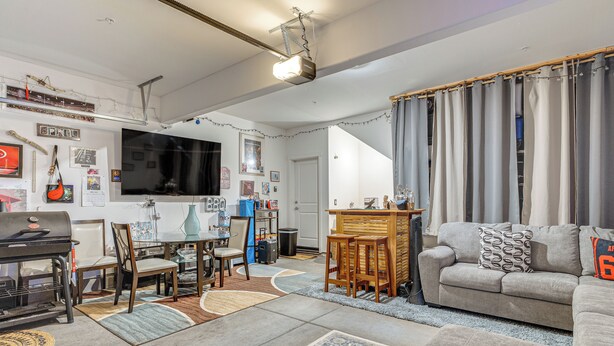 Un salon comprenant un canapé, un téléviseur, un barbecue et un coin repas avec des chaises et une table.