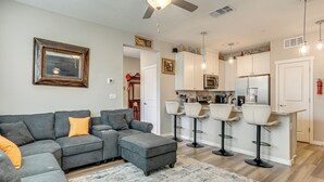 A modern living room with a sectional sofa, ottoman, and a bar area with stools. - Explore, Shop & Relax! Getaway in West Sacramento (West Sacramento)