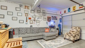 Un salon avec un canapé d’angle gris, un tapis à motifs, une table en bois et une chaise.