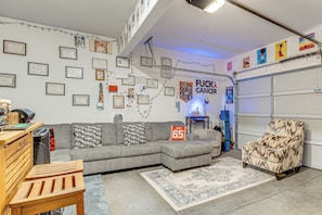 Sala de estar com sofá modular cinza, tapete estampado, mesa de madeira e uma cadeira.