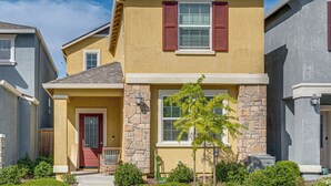 A two-story residential building with a stone facade, a red door, and a small porch with a chair. - Explore, Shop & Relax! Getaway in West Sacramento (West Sacramento)
