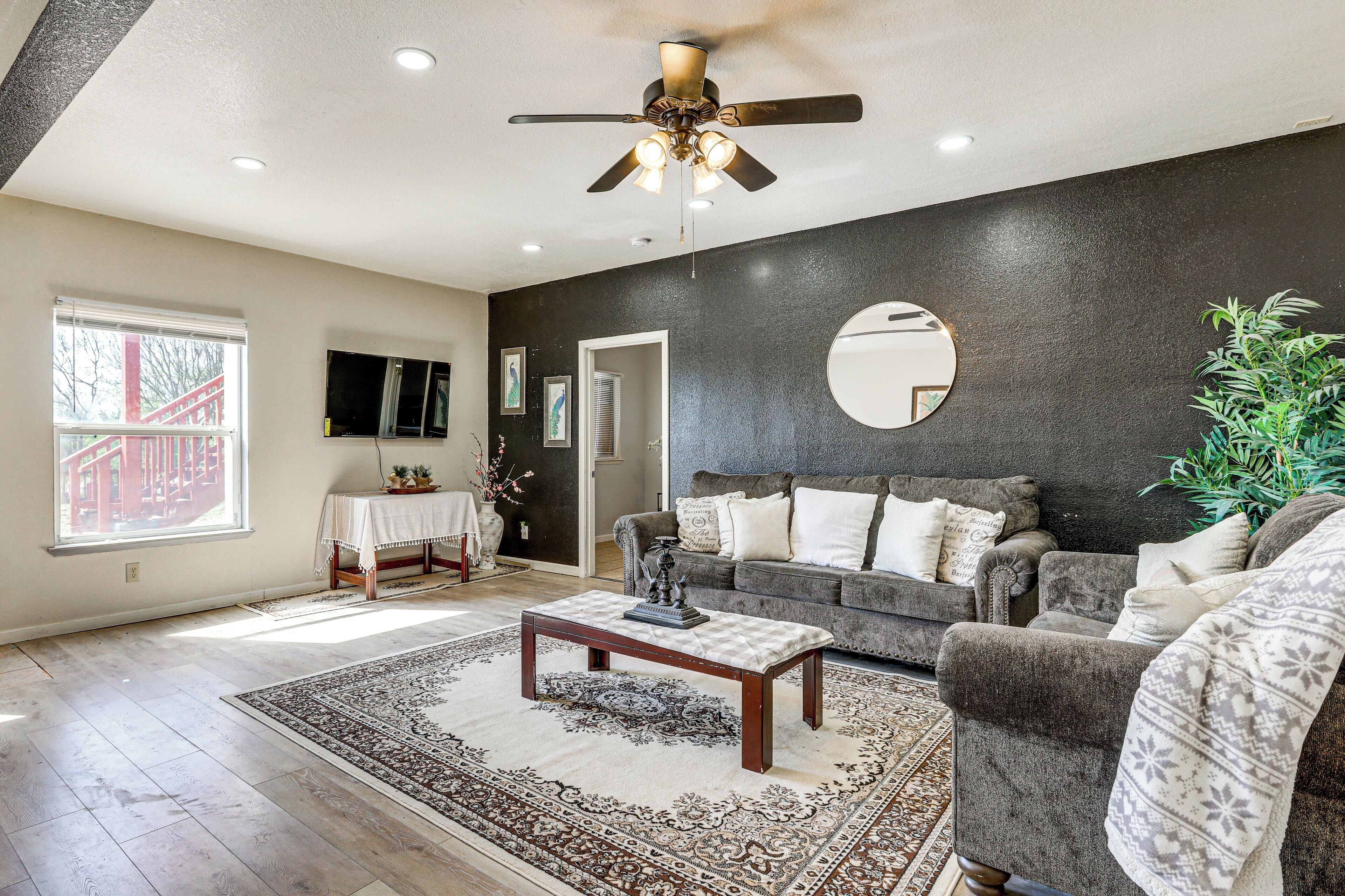 A living room with a ceiling fan, a gray sofa, a coffee table, and a large window.