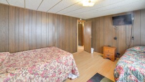 A bedroom with two beds, wooden walls, a ceiling light, and a television mounted on the wall. - Outdoor Adventure Base in the Heart of Miller (Miller)