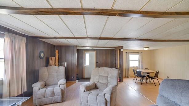 A spacious room with wooden floors, two armchairs, a dining table with chairs, and a door leading to another room. - Outdoor Adventure Base in the Heart of Miller (Miller)