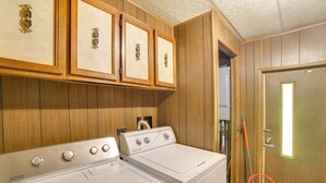 A laundry area with two white washing machines, wooden cabinets with decorative handles, and a mop leaning against the wall. - Outdoor Adventure Base in the Heart of Miller (Miller)