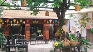 An outdoor seating area with tables and chairs, a tree, and a variety of decorative items including lanterns and baskets. - Daystar Hotel (Da Nang Municipality)