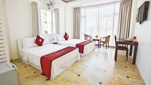 Quarto de hotel com duas camas, uma mesa de jantar, cadeiras, uma televisão e um ventilador.