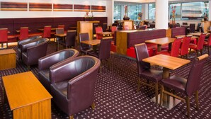 A restaurant with booths and tables, a patterned carpet, and a view of the street through large windows. - Holiday Inn Express Newcastle City Centre (Newcastle-upon-Tyne)