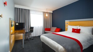 A hotel room with a bed, a desk with a chair, a television, and a window with curtains. - Holiday Inn Express Newcastle City Centre (Newcastle-upon-Tyne)