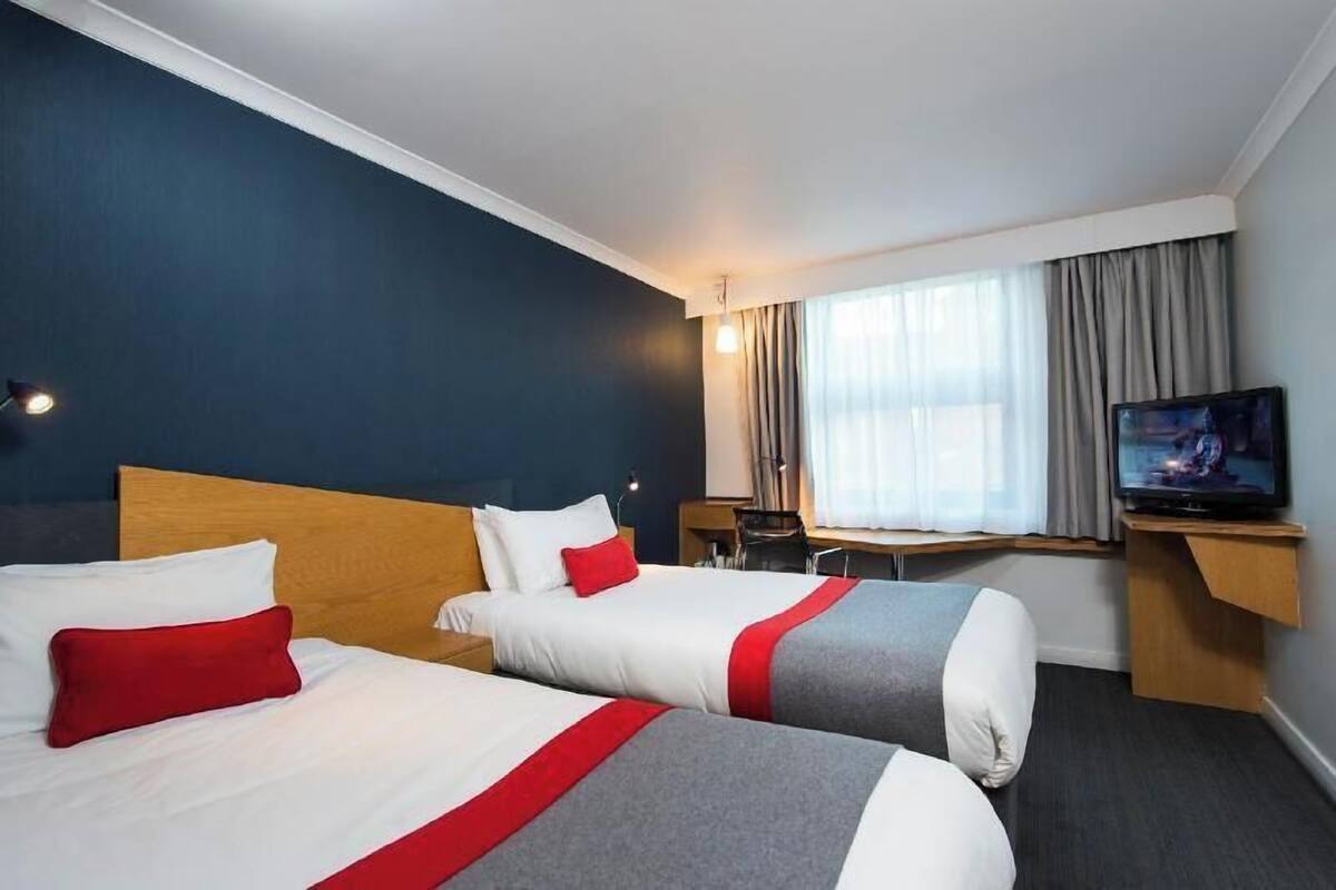 Habitación de hotel con dos camas, un televisor y un escritorio.