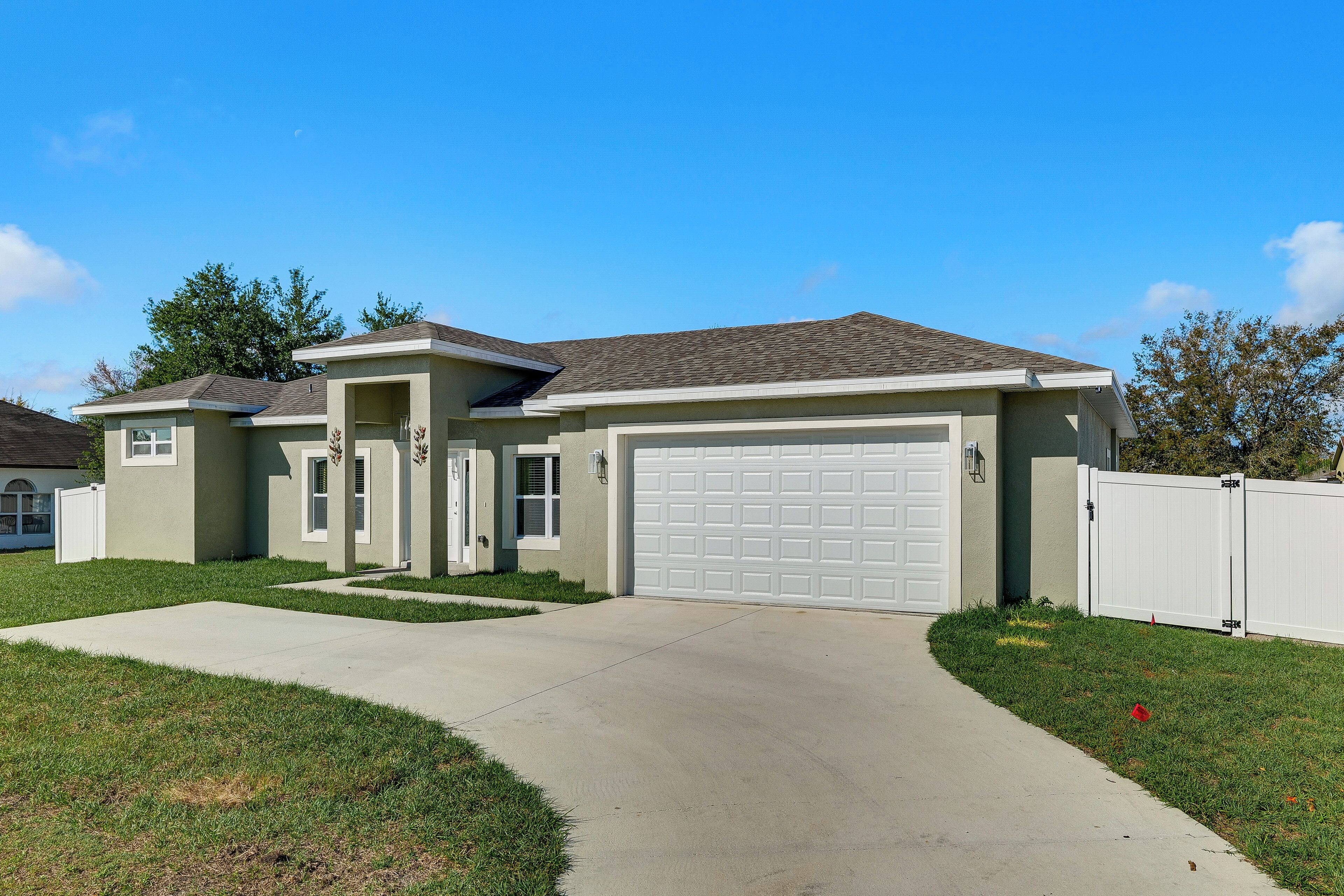 A single-story house with a garage, a driveway, and a well-maintained lawn.