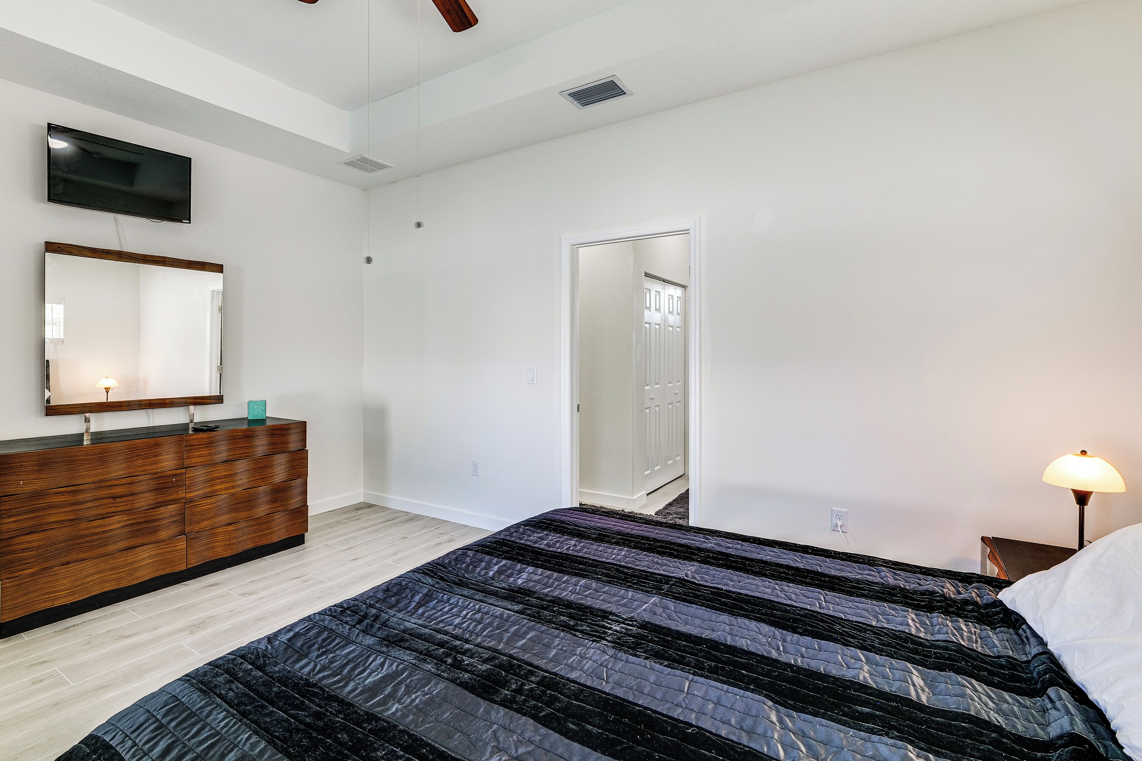 Un dormitorio con cama, cómoda, televisor y lámpara.
