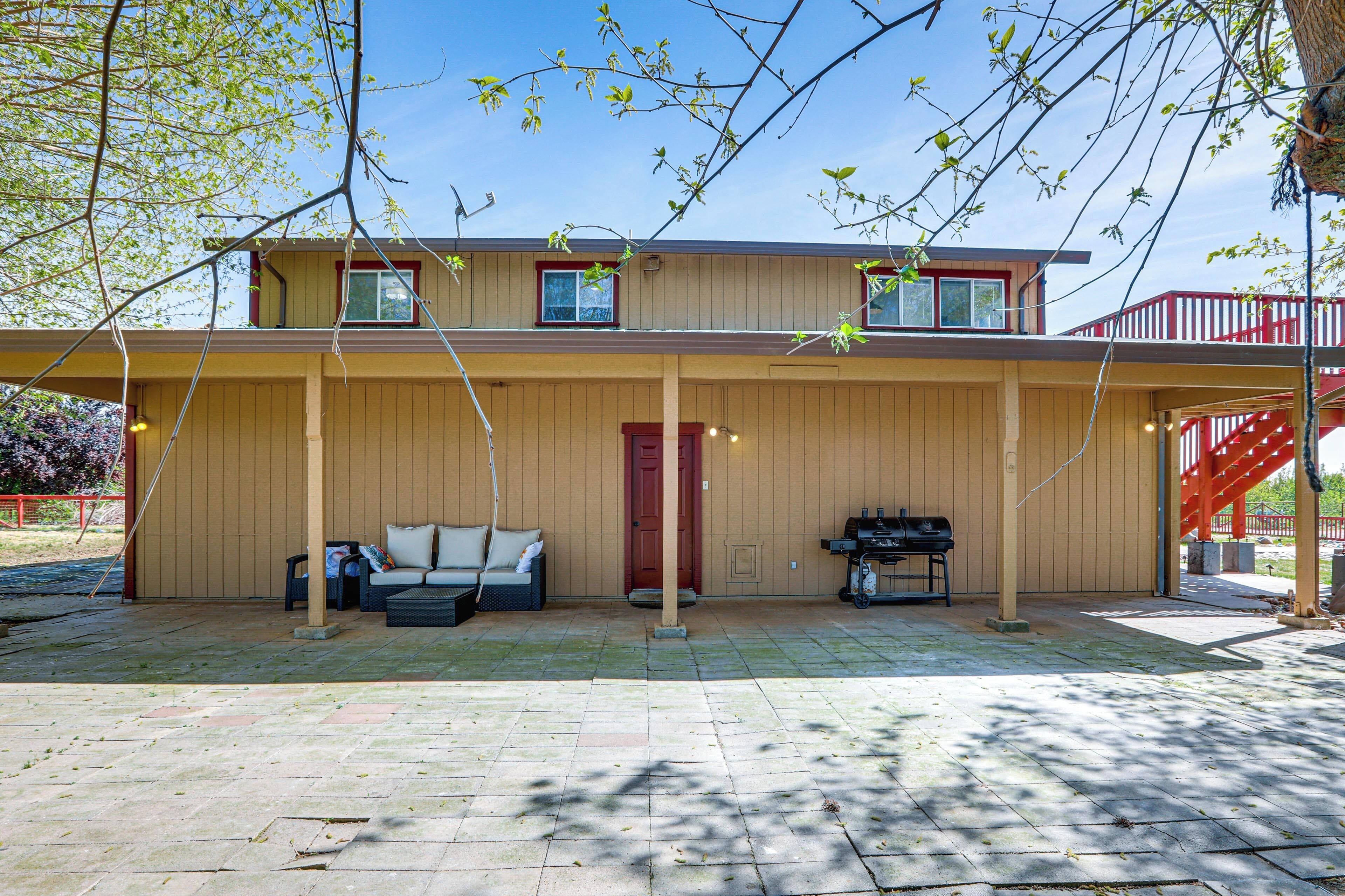 A two-story house with a covered porch, a red door, and a barbecue grill.