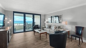 Ein modernes Wohnzimmer mit Balkon, einer Couch, einem Couchtisch und einem Sessel.