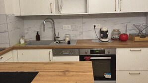 Eine kompakte Küche mit weißen Schränken, einer Holz Arbeitsplatte, einem integrierten Geschirrspüler und einem Backofen.