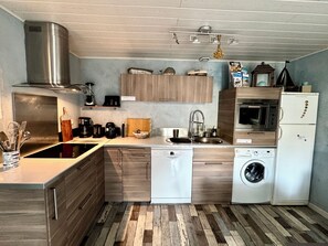 A compact kitchen with a dishwasher, washing machine, and a built-in oven. - The OUSTAOU of Boucanet • 25 m² terrace, private parking, beach 400 m away (Le Grau-du-Roi)