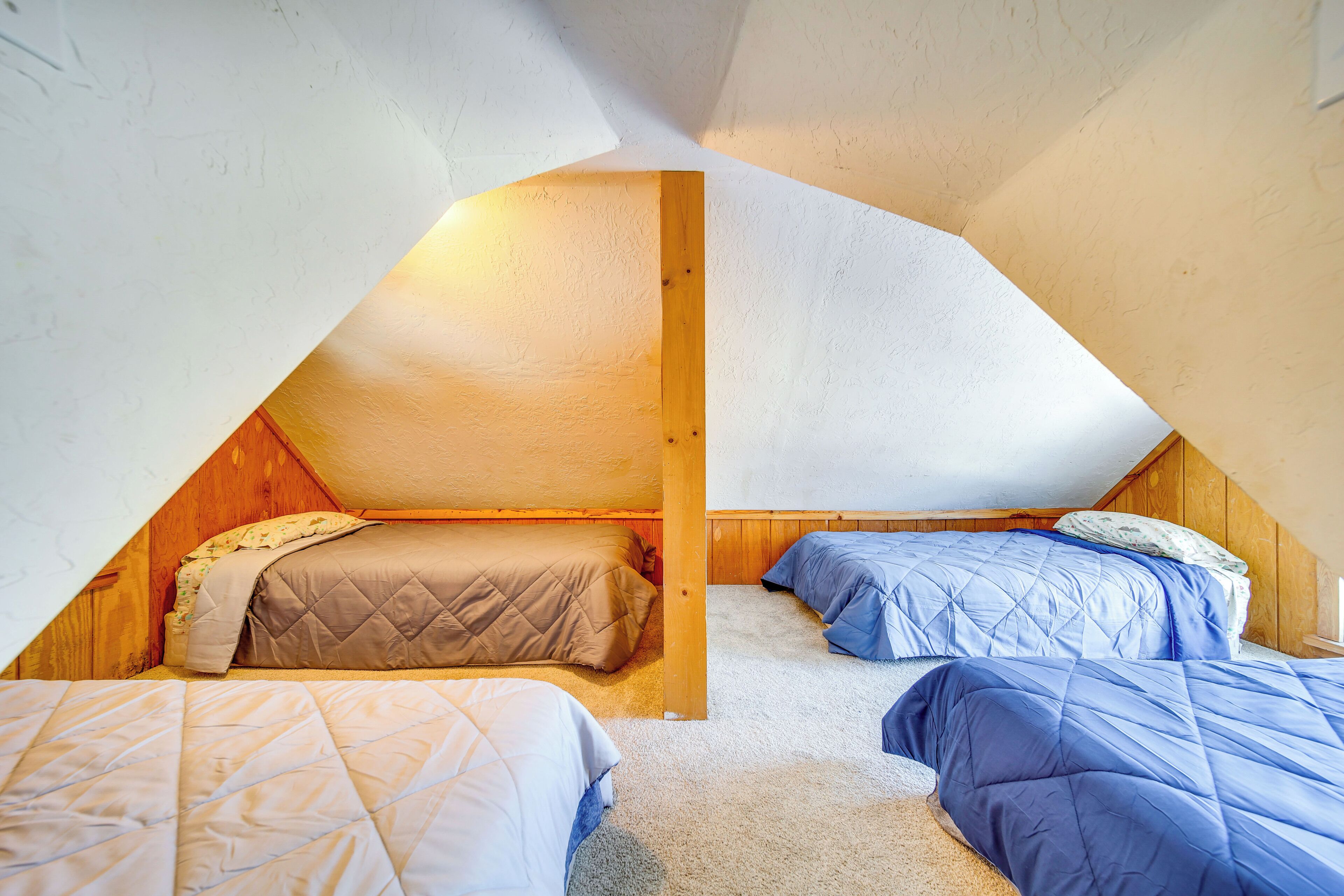 A small attic bedroom with two beds, wooden beams, and a sloped ceiling.