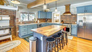 Una cocina con una isla grande, armarios azules, electrodomésticos de acero inoxidable y vigas de madera en el techo.