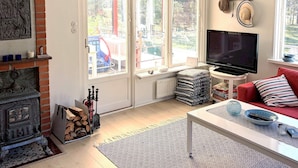 A living room with a fireplace, TV, and a red couch. - 4 Star Holiday Home in Yngsjo, Sverige (Yngsjo)
