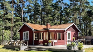 A red wooden cabin with a porch, steps, and potted plants. - 4 Star Holiday Home in Yngsjo, Sverige (Yngsjo)