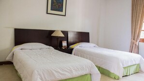 A hotel room with two beds, a nightstand with a lamp, and a framed picture on the wall. - Wisma Makara Universitas Indonesia (Jakarta)