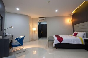 A modern hotel room with a bed, desk, chair, and a lamp. - Wisma Makara Universitas Indonesia (Jakarta)