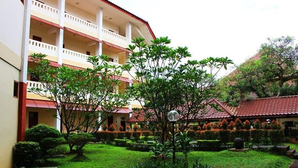 A multi-story building with a courtyard, surrounded by greenery and a red-tiled roof. - Wisma Makara Universitas Indonesia (Jakarta)