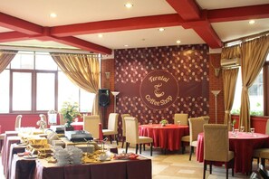 A coffee shop with tables set for dining, a stage with a speaker, and a wall with a coffee bean pattern. - Wisma Makara Universitas Indonesia (Jakarta)