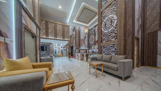 A spacious living area with a sofa, a coffee table, and a patterned wall. - Al Fakhama Aldahbai Al-Shohada (Madinah)