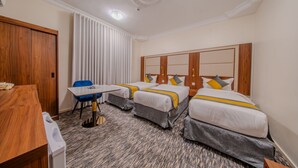 A hotel room with two beds, a desk, and a chair. - Al Fakhama Aldahbai Al-Shohada (Madinah)