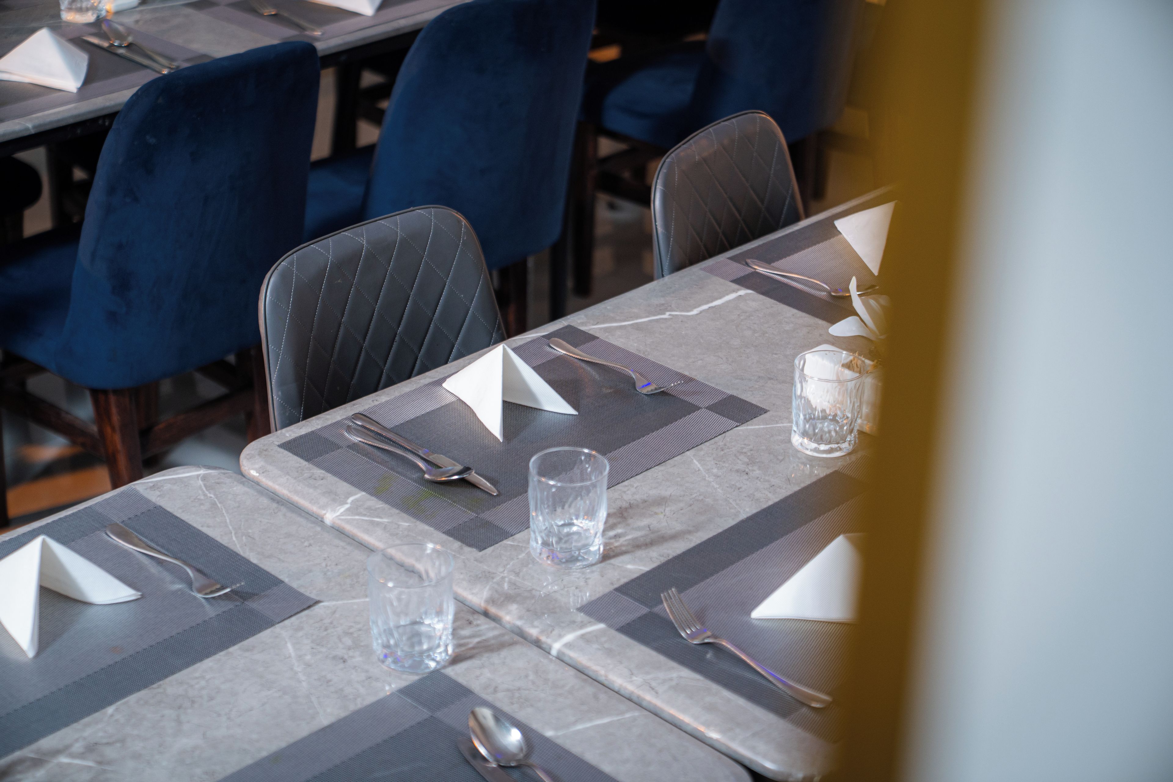 A table set for dining with a placemat, cutlery, and a glass of water.