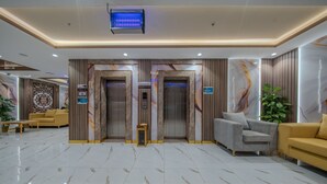 A lobby with marble flooring, two elevators, a reception desk, and seating areas. - Al Fakhama Aldahbai Al-Shohada (Madinah)