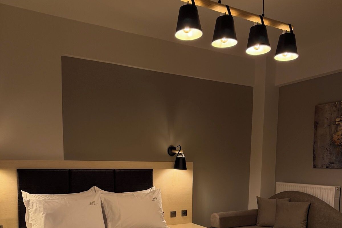 Une chambre moderne avec un grand lit, une table de chevet, une commode, un canapé et une lampe fixée au mur.