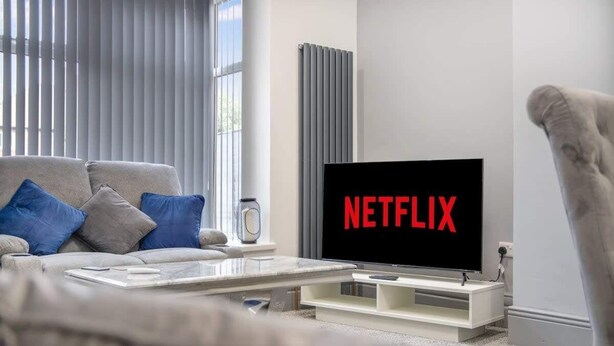 A modern living room with a sofa, coffee table, and a TV displaying 'NETFLIX'. - 3 Bedroom With Backyard, 10 Min to City Centre (Tyne and Wear)
