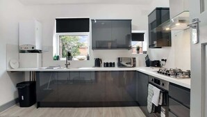 A modern kitchen with a large island, built-in appliances, and a window providing natural light. - 3 Bedroom With Backyard, 10 Min to City Centre (Tyne and Wear)