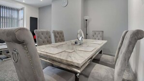 A conference room with a marble table, cushioned chairs, a clock, and a radiator. - 3 Bedroom With Backyard, 10 Min to City Centre (Tyne and Wear)