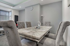 A conference room with a marble table, cushioned chairs, a clock, and a radiator. - 3 Bedroom With Backyard, 10 Min to City Centre (Tyne and Wear)